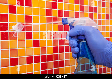 Person doing chores in bathroom at home cleaning tiled wall with spray detergent Stock Photo