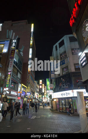 Brightly lit with neon signs the busy night time streets in central Seoul full of residents and tourists enjoying the restaurants and bars Stock Photo