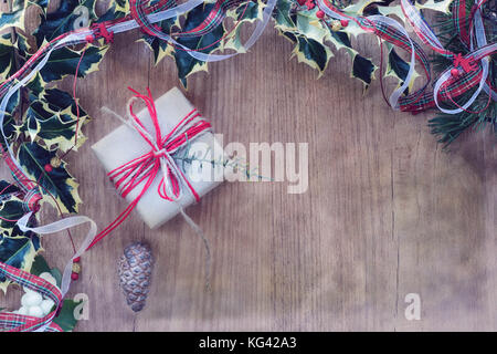 Gift boxes wrapped in rustic paper and rope. Photo frame with mistletoe and Christmas ribbon. Top view and copy space on wooden background. Stock Photo