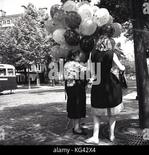 1950s, historical, a lady buying ballons from an elderly female street vendor in Paris, France. Stock Photo