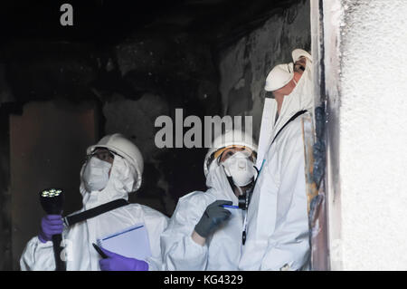 Fire investigation officers examine the scene of a fatal house fire to determine the cause of the incident. Stock Photo