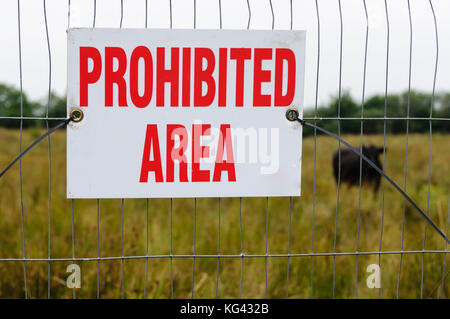 Sign on a fence beside a field 'Prohibited Area' Stock Photo