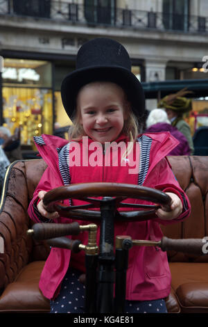 London, UK. 4th November, 2017. A young girl sits with a top hat on in the drivers seat at the Regent Street Motor show which took place ahead of the London to Brighton Veteran Car Run tomorrow. Veteran, classic and modern cars were on display along with people dressed in period costumes. The run starts from Hyde Park tomorrow at sunrise. © Keith Larby/Alamy Live News Stock Photo