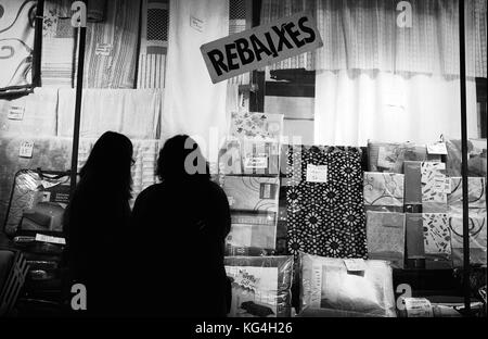 Two women look at the shop window for sell out prices from the extinct El Indio shop that use to be in the Carme street of Barcelona, Spain. Date: 05/12/2014.  Photo: Xabier Mikel Laburu. Dating back to the 1850's this shop was one of the referents in cloth sales in Barcelona and the rest of Spain. After the civil war the owners disappeared and the father from the last owner of the shop (Victor Riera), who was a worker in the shop at the time, found the way to buy it with help of a parter in 1940. Victor Riera, would take over the shop in 1970 and would keep it working until December 31st of 2 Stock Photo
