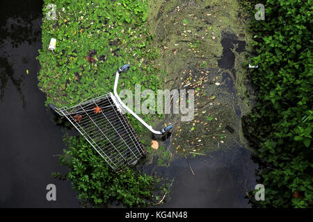 An abandoned shopping trolley dumped in a local river causing  environmental damage in Bristol, England, UK Stock Photo