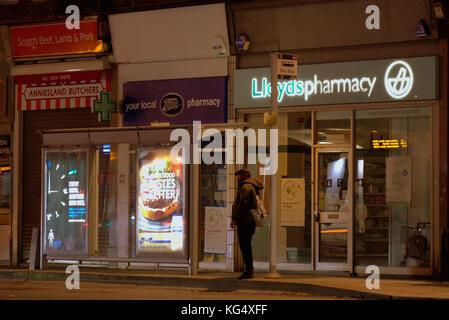 man waiting at bus stop on street for late night bus anniesland cross glasgow Stock Photo