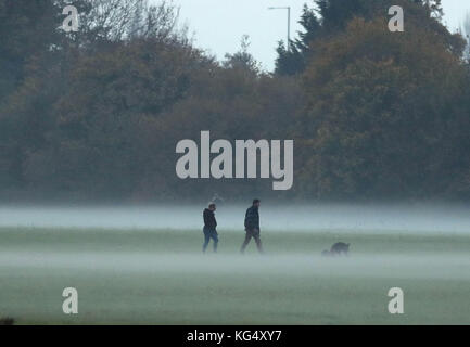 People walk their dogs in the mist near Eton, Berkshire, after London and the south east had a Met Office yellow warning of fog issued last night. Stock Photo