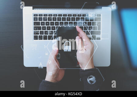 cyber security internet and networking concept.Businessman hand working with VR screen padlock icon mobile phone on computer background Stock Photo