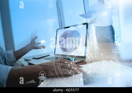 Hands of businessman using mobile phone in modern office with laptop and digital tablet computer in team meeting with VR icon diagram Stock Photo