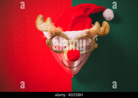Christmas glasses that decoration with reindeer and red hat on air bolloon on green and red background Stock Photo