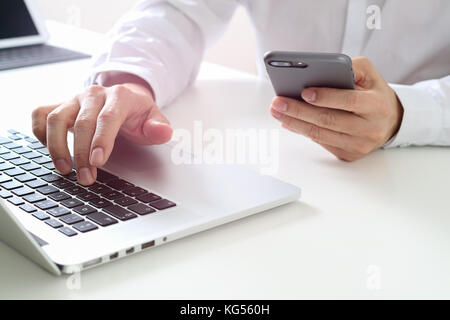 Big data analytics with business intelligence (BI) concept. businessman using mobile phone and laptop computer on white desk Stock Photo