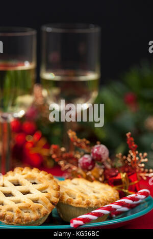 Lattice top mince pies on a plate and two glasses of white wine on a table decorated for christmas Stock Photo