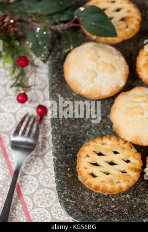 Selection of fresh frosted mince pies on a tray with festive christmas decorations on a country table Stock Photo