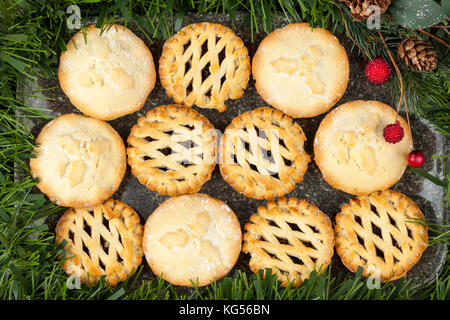 Selection of fresh golden brown mince pies on a marble platter festively decorated for christmas Stock Photo