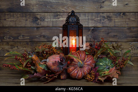 Burning lantern with autumn decorations on a wood background Stock Photo