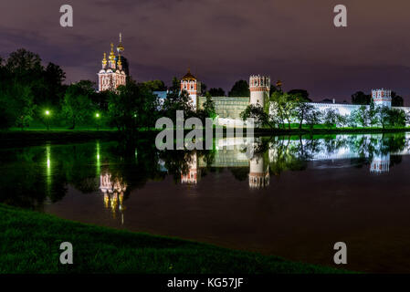 Picturesque night view of Moscow with the Novodevichy monastery, white stone walls, green trees, lights and beautiful reflections of them in the water Stock Photo