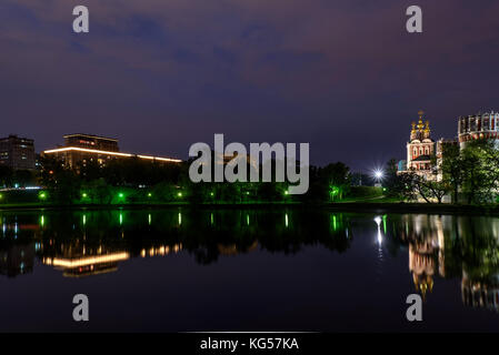 Picturesque night view of Moscow with the Novodevichy monastery, white stone walls, green trees, lights and beautiful reflections of them in the water Stock Photo