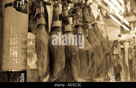 butcher posing among jams hanging from the ceiling Stock Photo