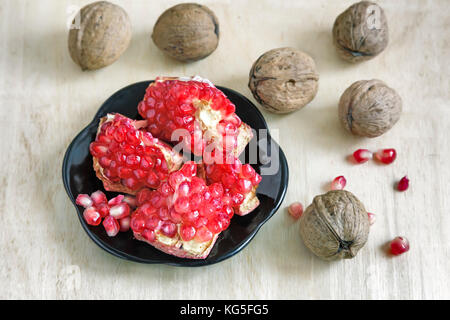 Pomegranate fruits on the plate and walnuts. Stock Photo