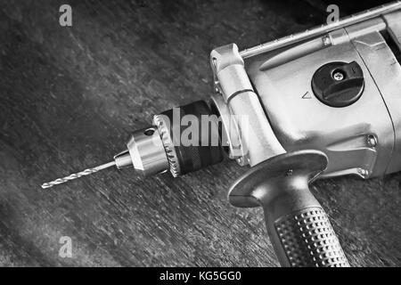 On a carpenter's workbench lies a compact electric hand drill. Stock Photo