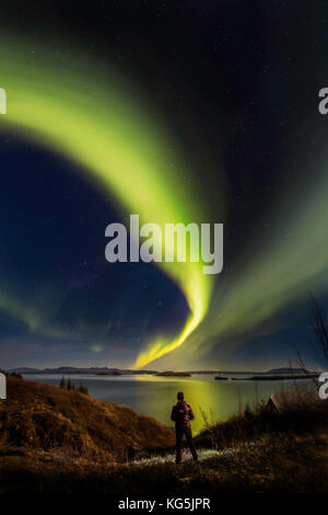 Woman enjoying the view of the Northern Lights, at Lake Thingvellir, Iceland. Thingvellir National Park is a UNESCO World Heritage Site. Stock Photo