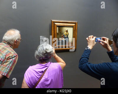 Visitors at Rijks Museum are admiring panting 'Milkmaid' by Johannes Vermeer (1632-16750) Stock Photo