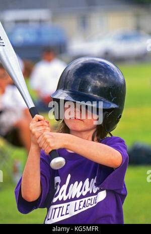 A young girl playing Little League Baseball, waits for a pitch from the pitcher. Stock Photo