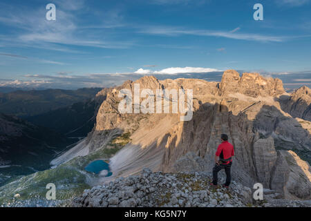 Sesto / Sexten, province of Bolzano, Dolomites, South Tyrol, Italy. A mountaineer admires the alpenglow at the summit of Mount Paterno Stock Photo