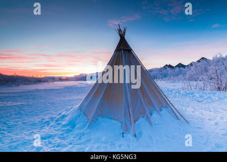 Pink sky at sunrise on isolated Sami tent in the snow, Abisko, Kiruna Municipality, Norrbotten County, Lapland, Sweden Stock Photo