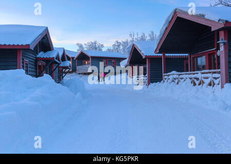 People walk through the snowy streets of the village. Bjorkliden, Norbottens Ian, Sweden, Europe Stock Photo