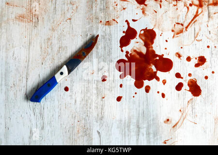 Conceptual image of a sharp knife with blood on it resting on the floor. Kitchen knife in red blood on a white vintage background Stock Photo