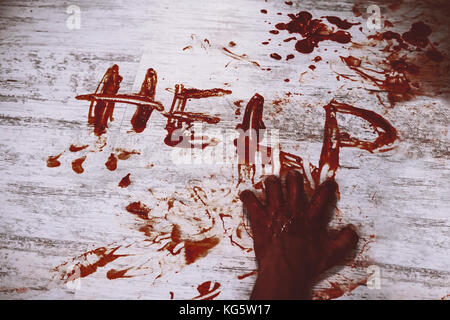 Says help, written in red blood on the dirty white floor of the bloody hand. The murder victim asks for help. Stock Photo