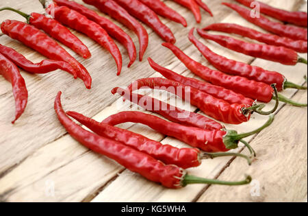 red hot chili peppers drying on wooden background Stock Photo