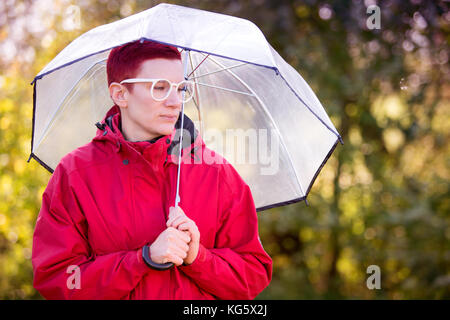 portrait of red-haired woman in red coat with umbrella Stock Photo