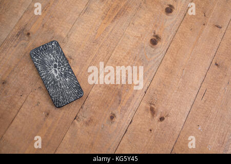 Crushed smartphone on a wooden table Stock Photo