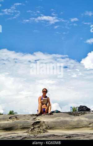 Caucasian woman reads a book in the beautiful beach under blue sky Stock Photo