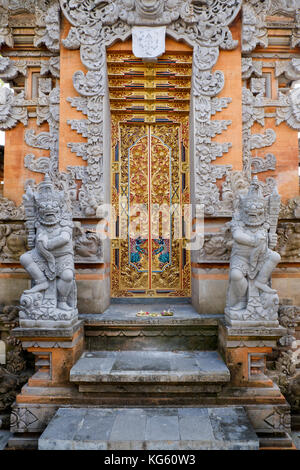 Gate of traditional Balinese compound flanked by two 'dvarapala' (guardian) statues, Ubud, Bali, Indonesia. Stock Photo