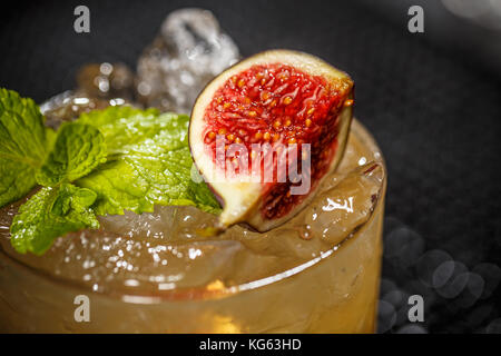 Close up of glass with iced refreshing cocktail with fig and mint leaf Stock Photo