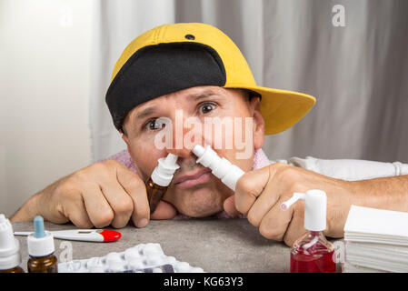 Cold concept. Sick man with the flu taking nasal spray. Stock Photo