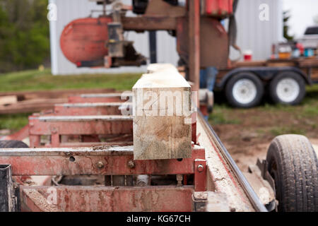 block or beam of wood being milled on a portable milling machine or saw outdoors in a timber yard with a close up view on the end Stock Photo