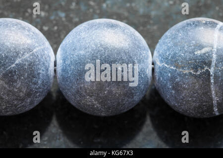macro shooting of natural mineral rock specimen - necklace from Shungite gemstone on dark granite background Stock Photo