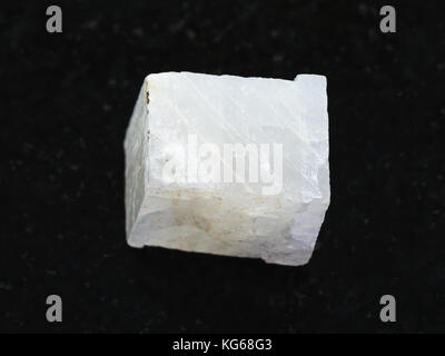 macro shooting of natural mineral rock specimen - rough white calcite stone on dark granite background Stock Photo