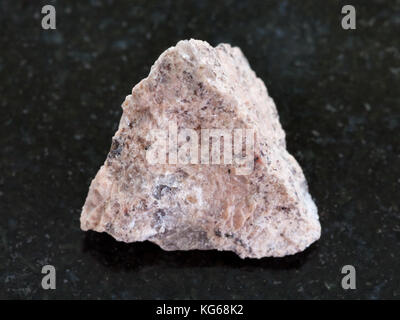 macro shooting of natural mineral rock specimen - rough Granite stone on dark granite background Stock Photo