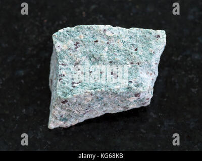 macro shooting of natural mineral rock specimen - rough Trachyte stone on dark granite background Stock Photo