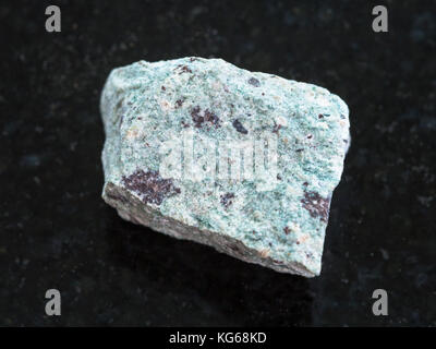 macro shooting of natural mineral rock specimen - raw Trachyte stone on dark granite background Stock Photo