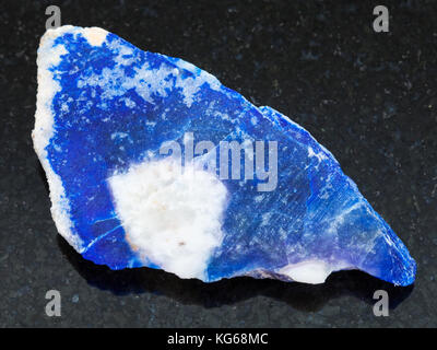 macro shooting of natural mineral rock specimen - rough lazurite (lapis lazuli) stone on dark granite background Stock Photo