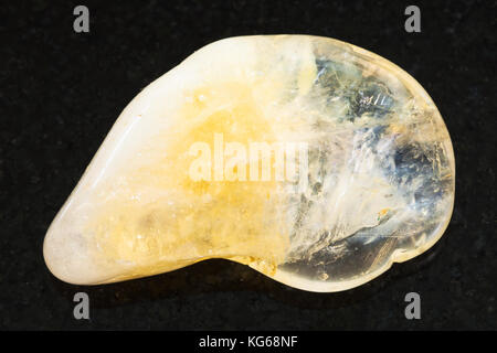 macro shooting of natural mineral rock specimen - polished yellow Citrine gemstone on dark granite background Stock Photo