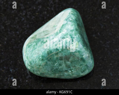 macro shooting of natural mineral rock specimen - polished green Jadeite gemstone on dark granite background Stock Photo