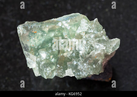 macro shooting of natural mineral rock specimen - green crystalline fluorite gemstone on dark granite background from Usugli region of Zabaykalsky Kra Stock Photo