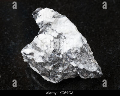 macro shooting of natural mineral rock specimen - native Bismuthinite in rough quartz stone on dark granite background from Malkhanskoye mine (Malkhan Stock Photo